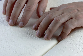 Finger ertasten einen Text in Brailleschrift
